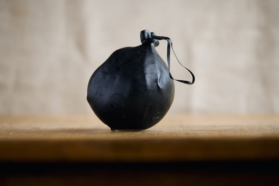 Black cheese bomb on a wooden surface with a neutral background