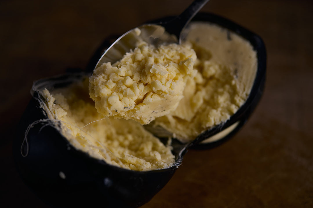 Scoop of cheese n a black bowl with a blurred background