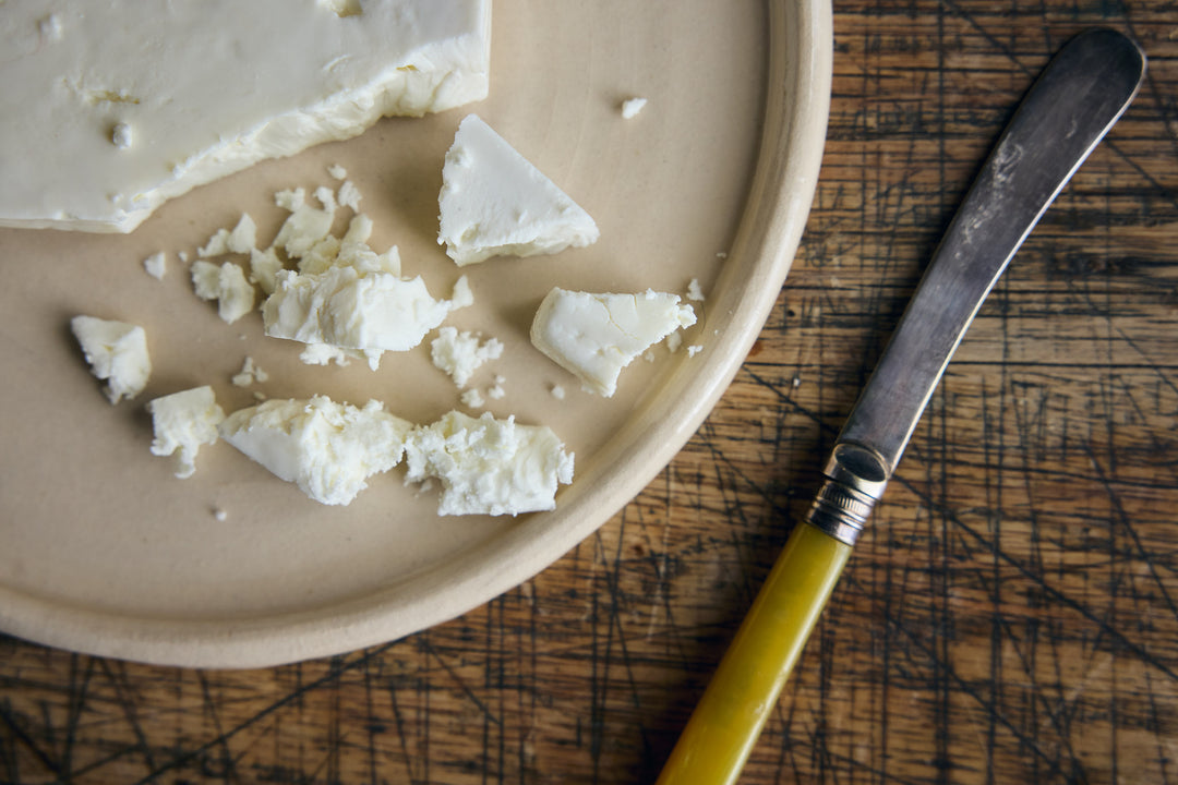 Cheese on a plate with a knife on a wooden surface