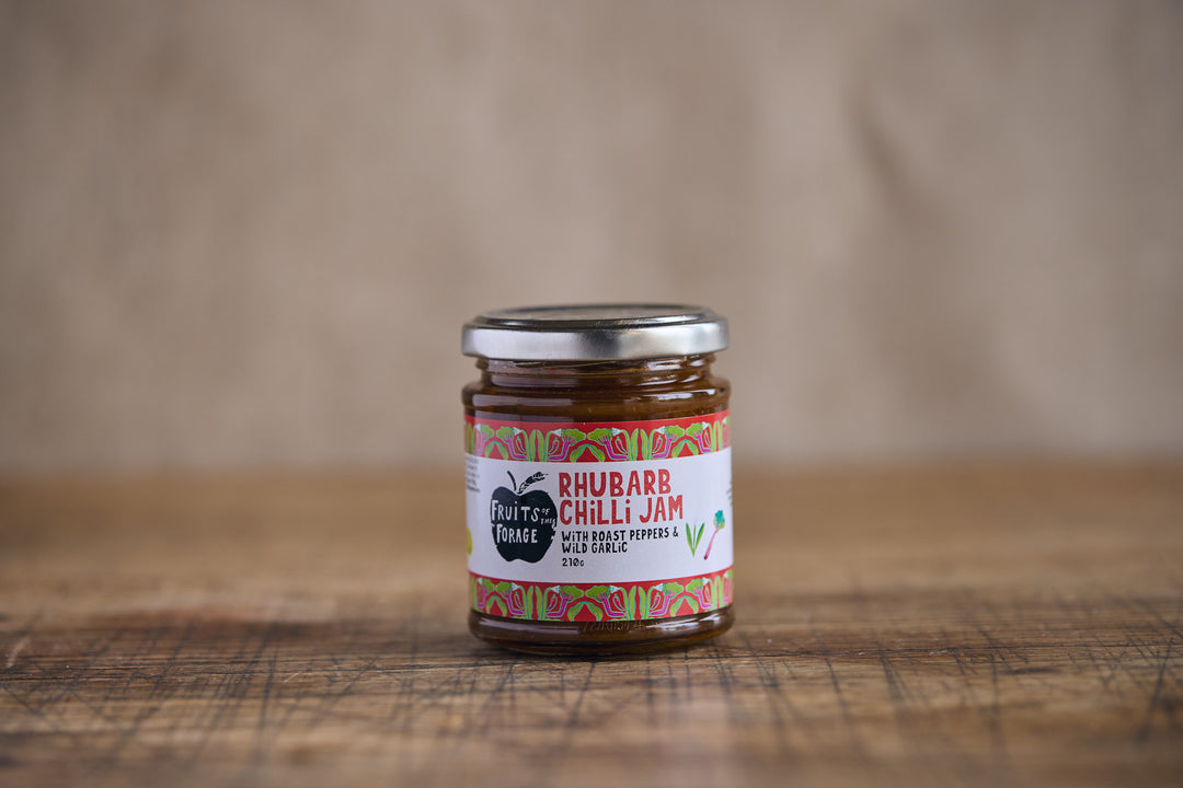 Jar of rhubarb chili jam on a wooden surface with a blurred background