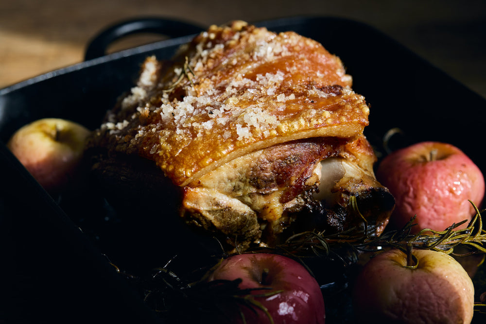 Roasted pork shoulder with apples in a black cast iron skillet